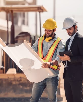 Civil engineer and construction worker manager holding digital tablet and blueprints , talking and planing about construction site.  Cooperation teamwork concept.