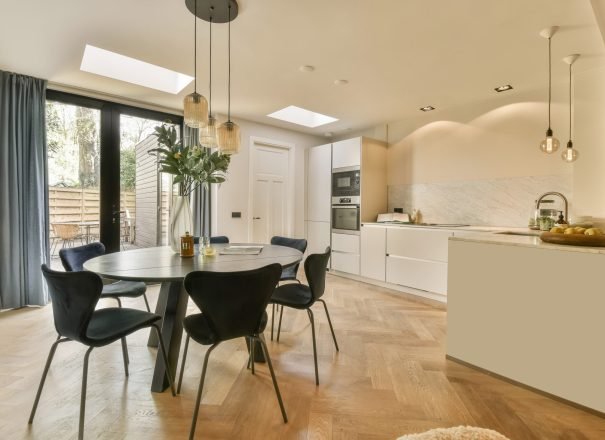 a kitchen and dining room with a table and chairs a kitchen and dining area in a modern home with wood flooring, white walls, wooden floors and skylights